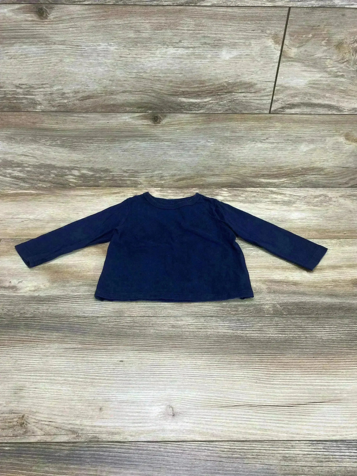Flat lay of Children’s Place Long Sleeve Shirt Navy sz 9-12m showcasing plain navy long-sleeve tee on wood plank background