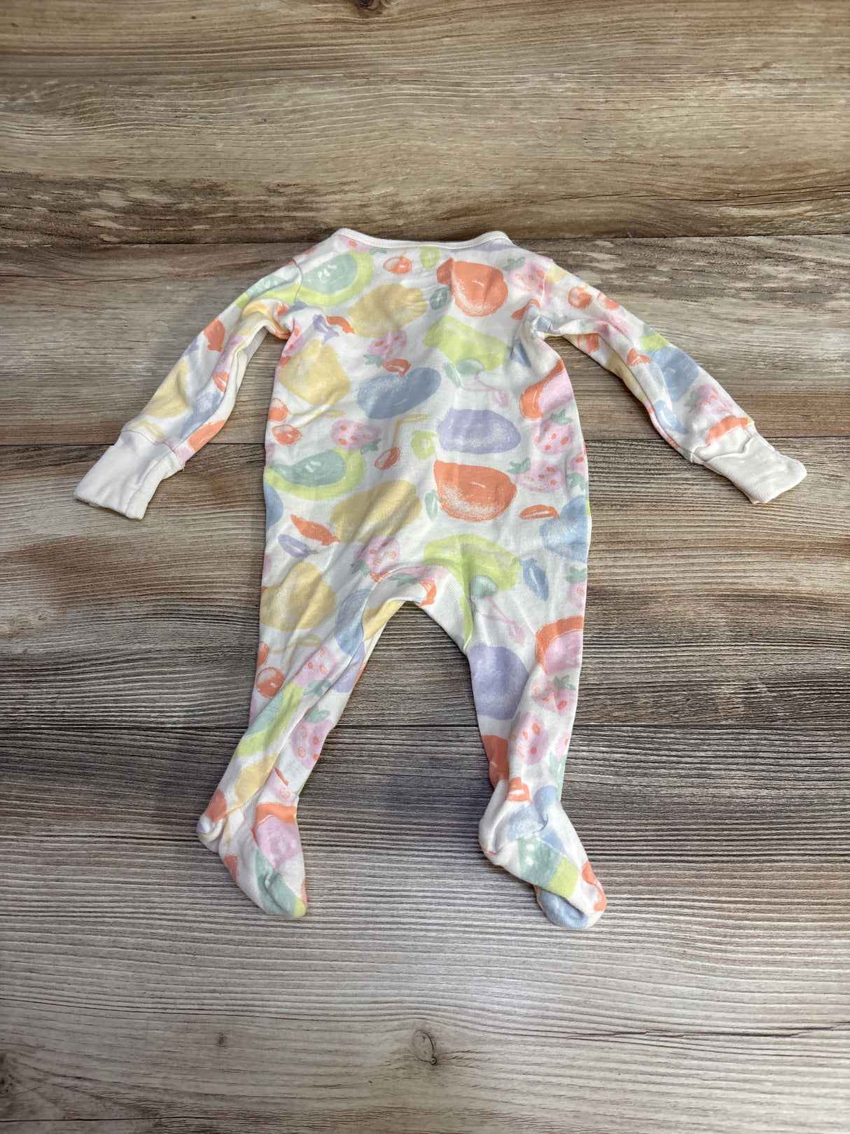 Colorful fruit print baby footed onesie on wood floor background