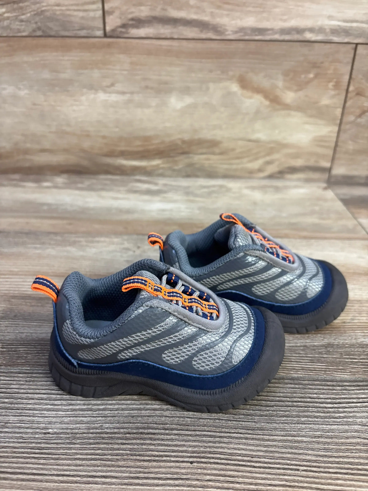 Angled view of Oshkosh Gianni bump toe sneakers showcasing reinforced toe protection with a wood-look floor background