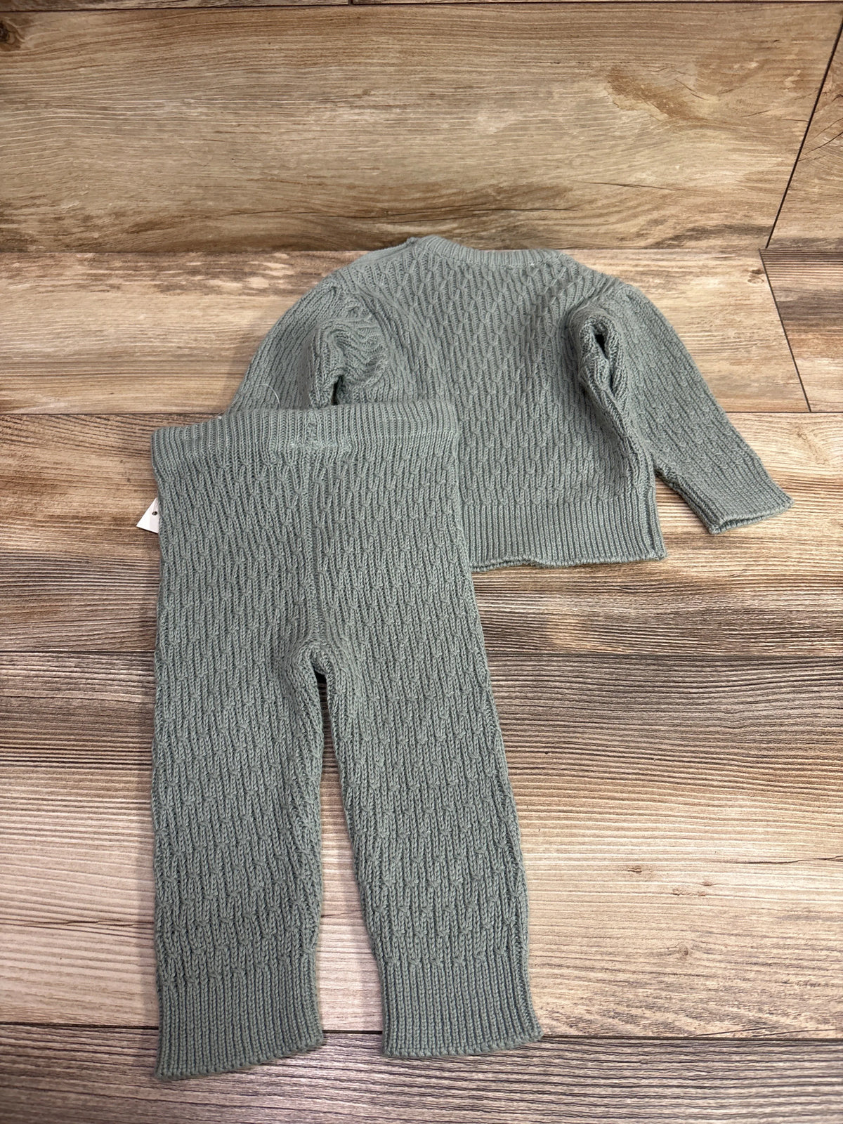 Jessica Simpson 2-piece sage green knit sweater and pants set for infants on a wood background