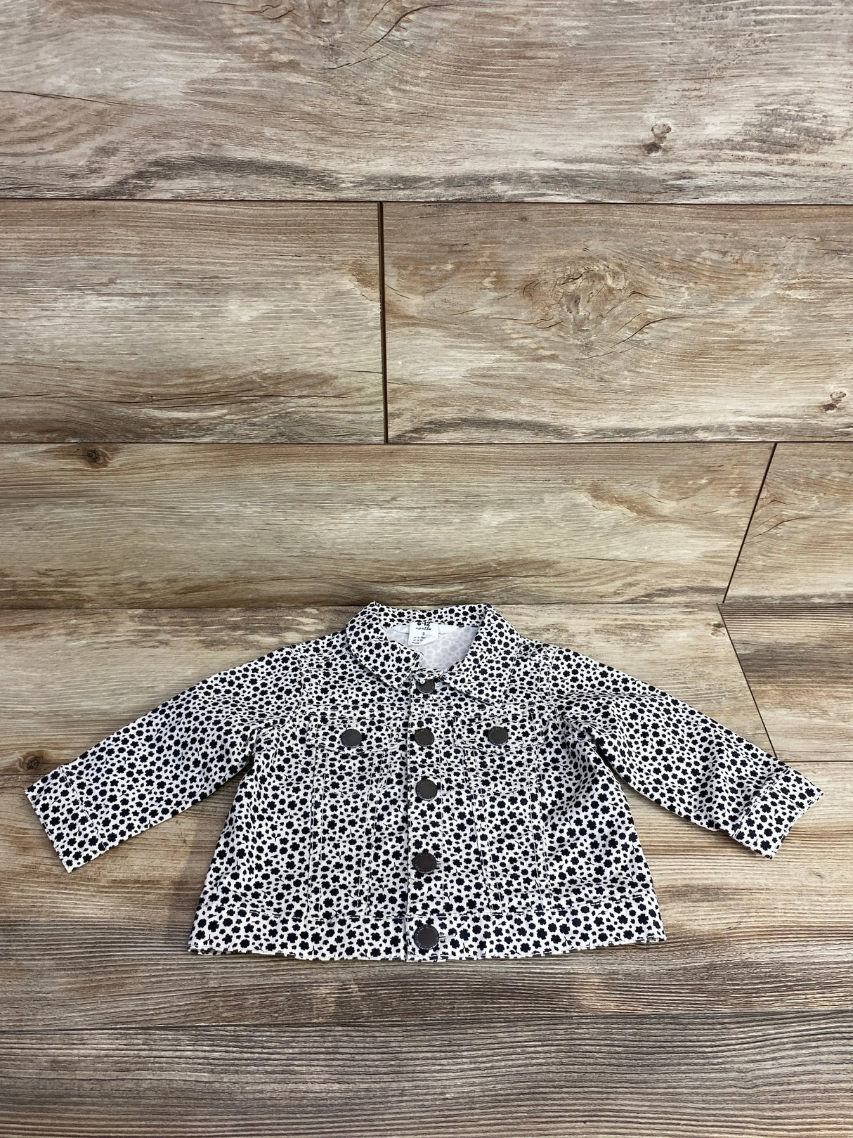 children's black and white floral print button-up jacket on wooden background