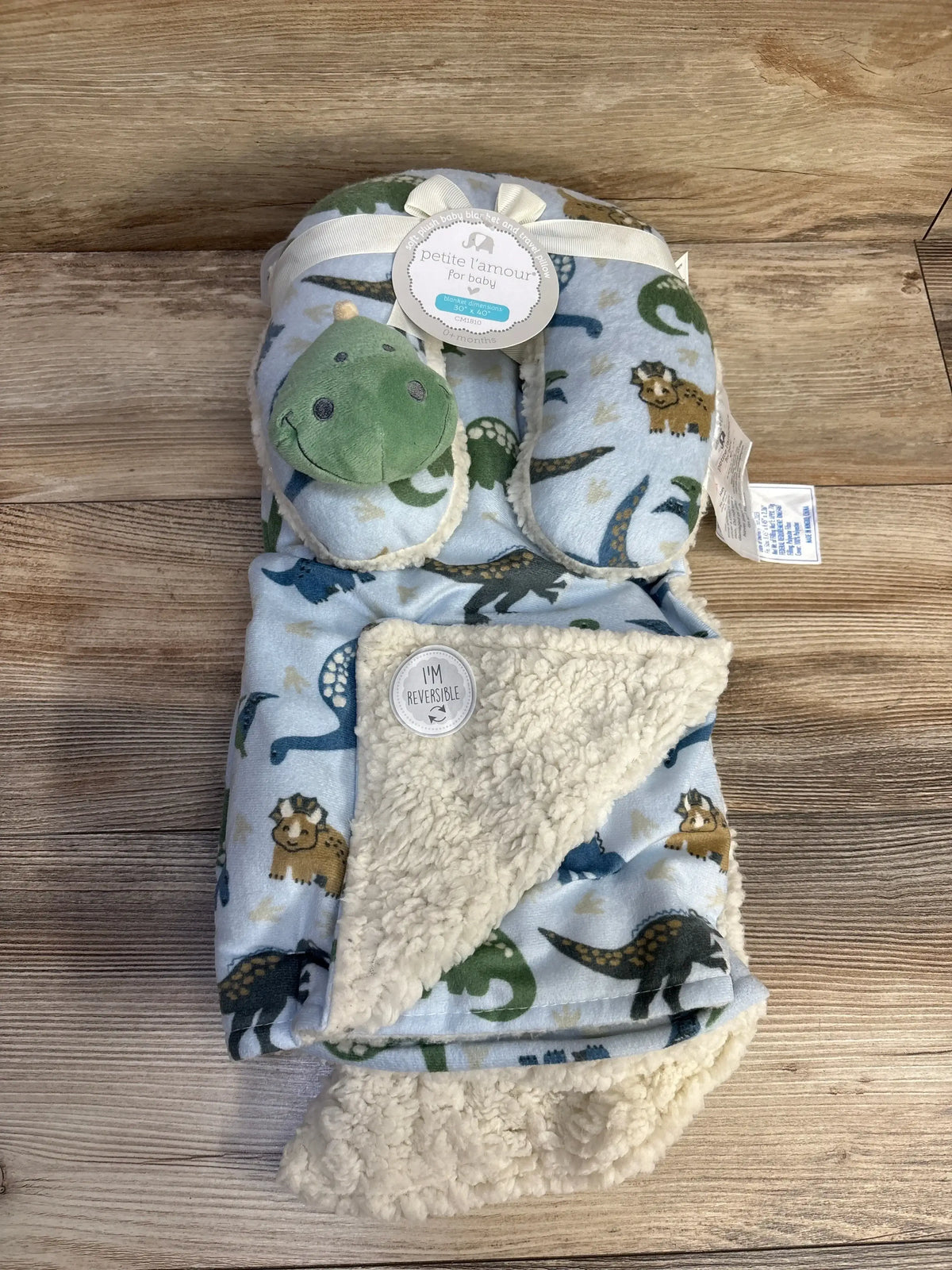 Baby blanket and travel pillow set with dinosaur print and plush green dino head, reversible fleece lining