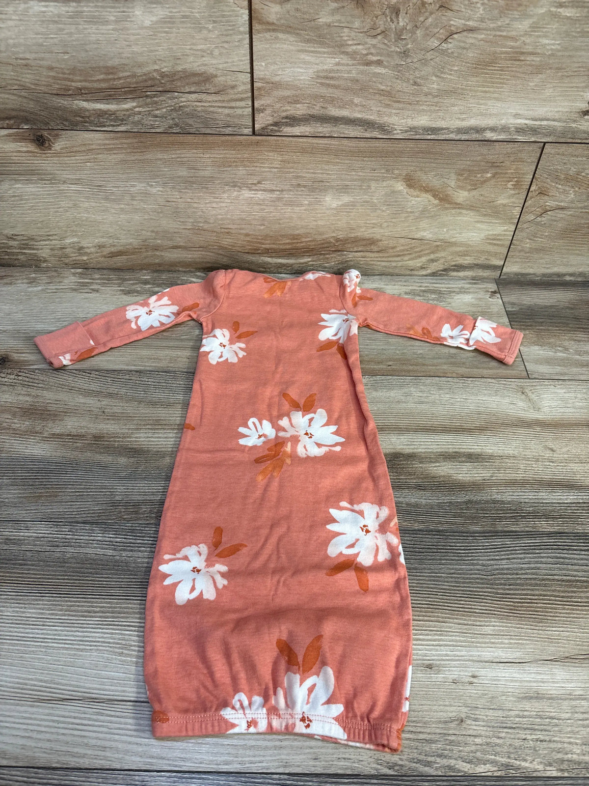 Front view of Carter’s coral sleep gown in size 3 months showcasing long sleeves and white floral print with a wood-grain background