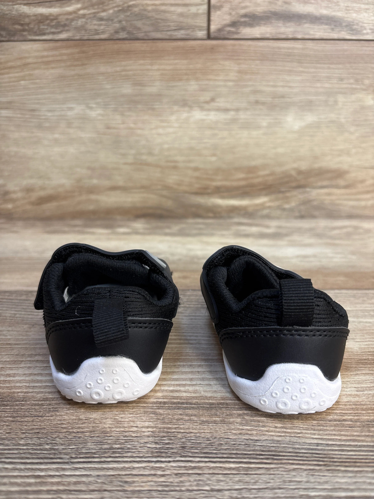 Black and white baby sneakers with velcro straps, perfect for first walkers and toddler footwear.