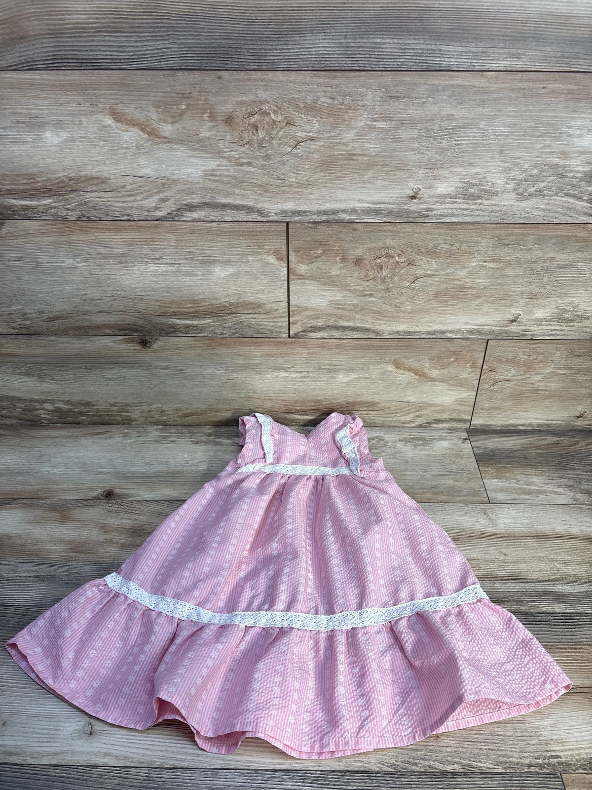 Flat lay of RZ by Rachel Zoe pink lace trim toddler dress in size 4T showcasing tiered skirt on wood planks