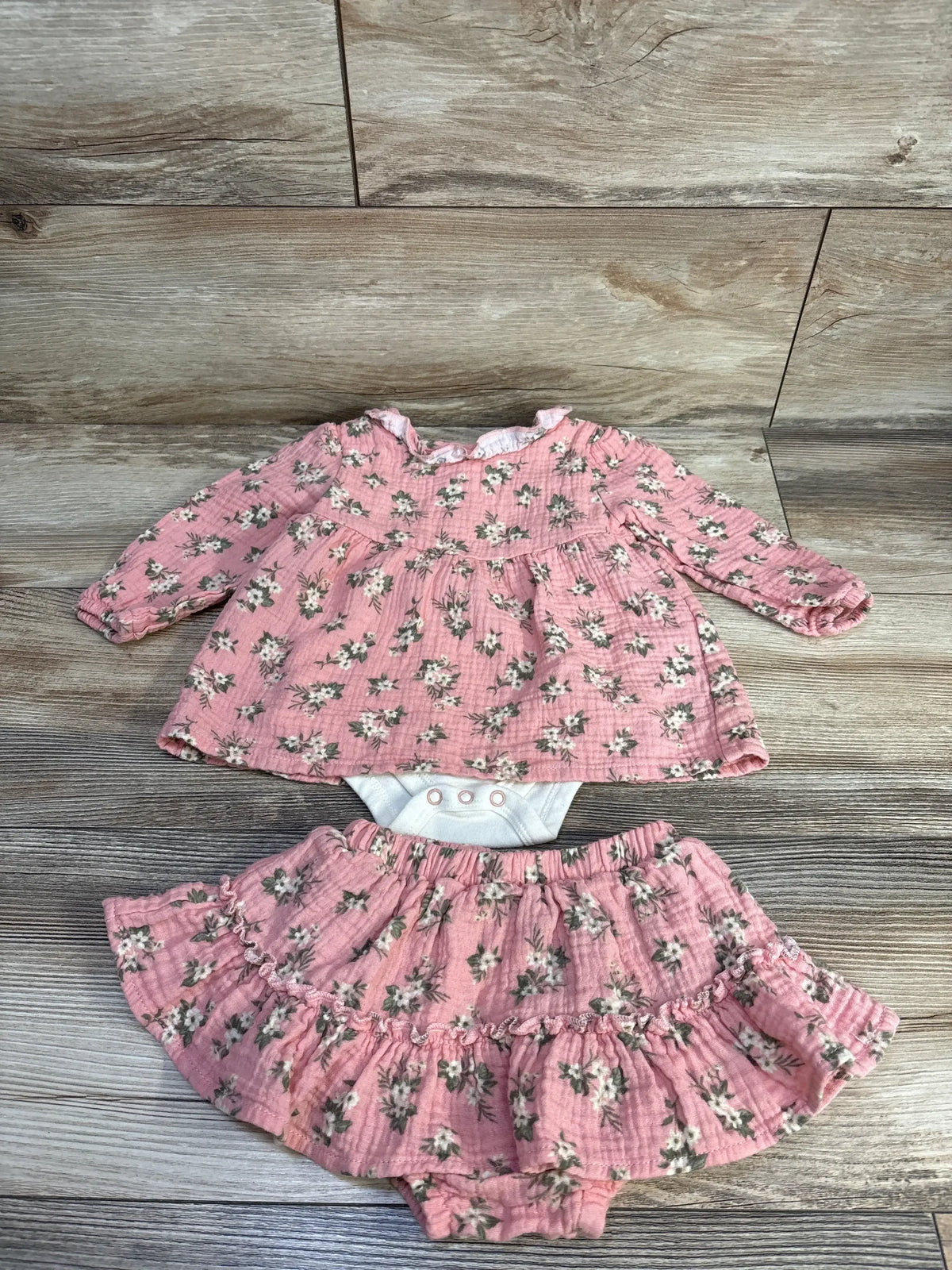 Front view of Nicole Miller pink floral bodysuit and bloomers showcasing long sleeves on a wood look floor