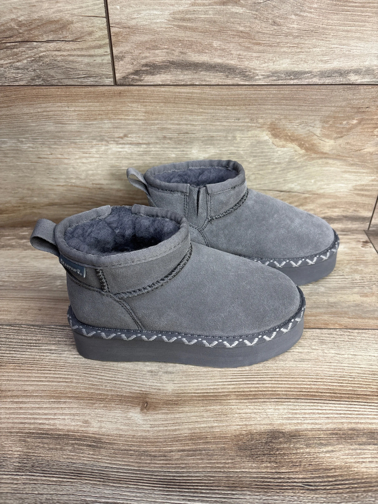 Gray suede kids boots with faux fur lining on wooden background