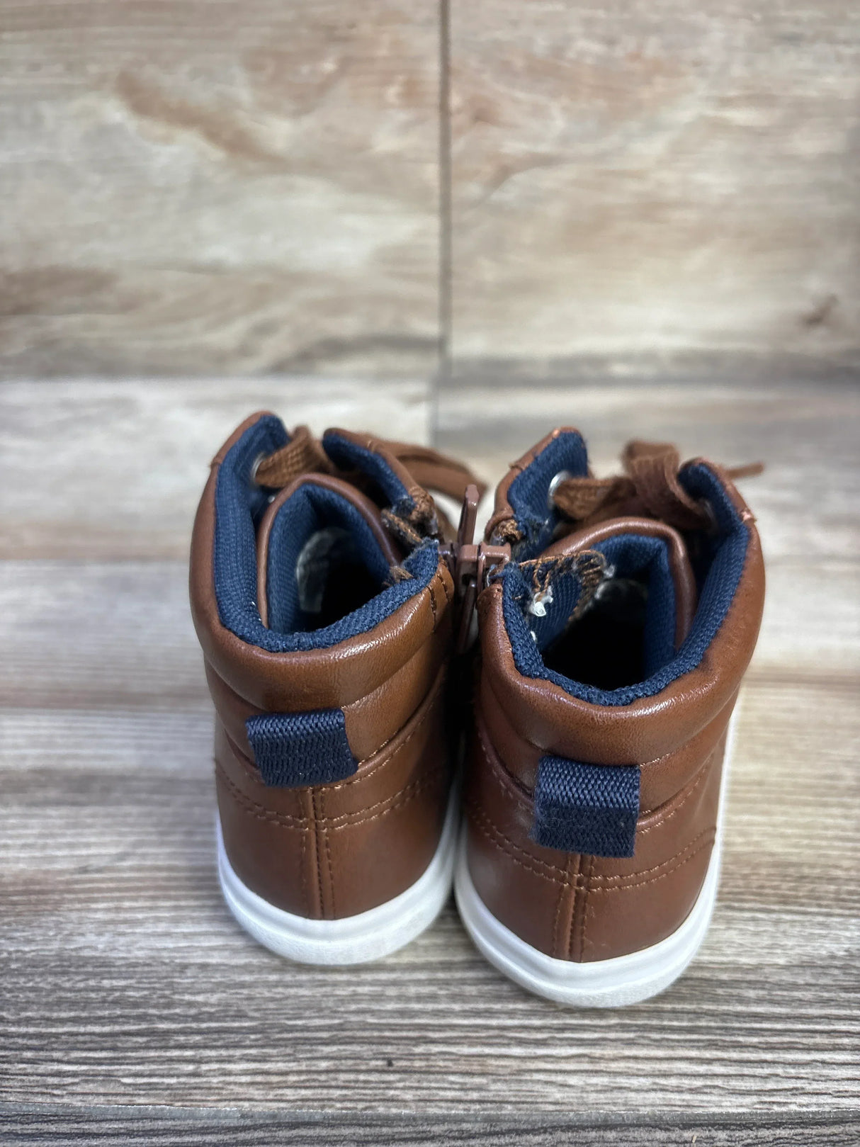 Rear view of Cat and Jack Mateo brown high-top toddler sneakers showing navy heel loops and white soles on wood floor