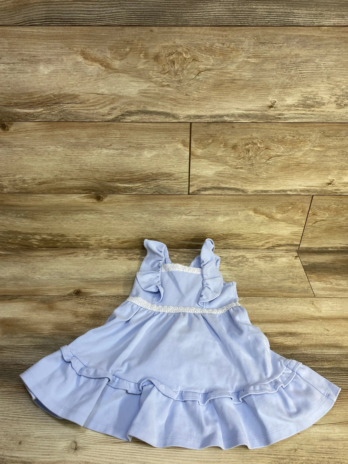 Top-down view of Janie & Jack Ruffle Ponte dress (3T) showing ruffled straps, lace waist trim, and ruffled hem on wood floor