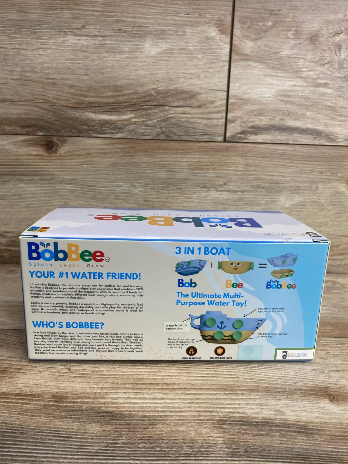 Front view of BobBee 3-in-1 boat bath toy box showcasing colorful boat graphic, silicone suction cups and 3 in 1 label on a wooden surface