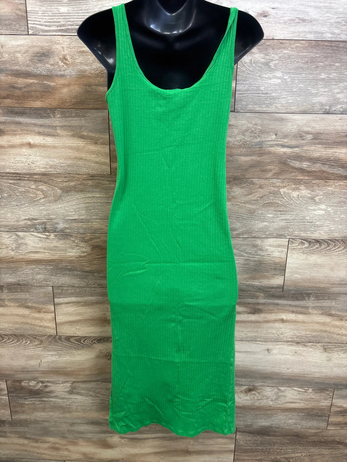 Front view of green ribbed sleeveless maternity midi dress on black mannequin against wood backdrop