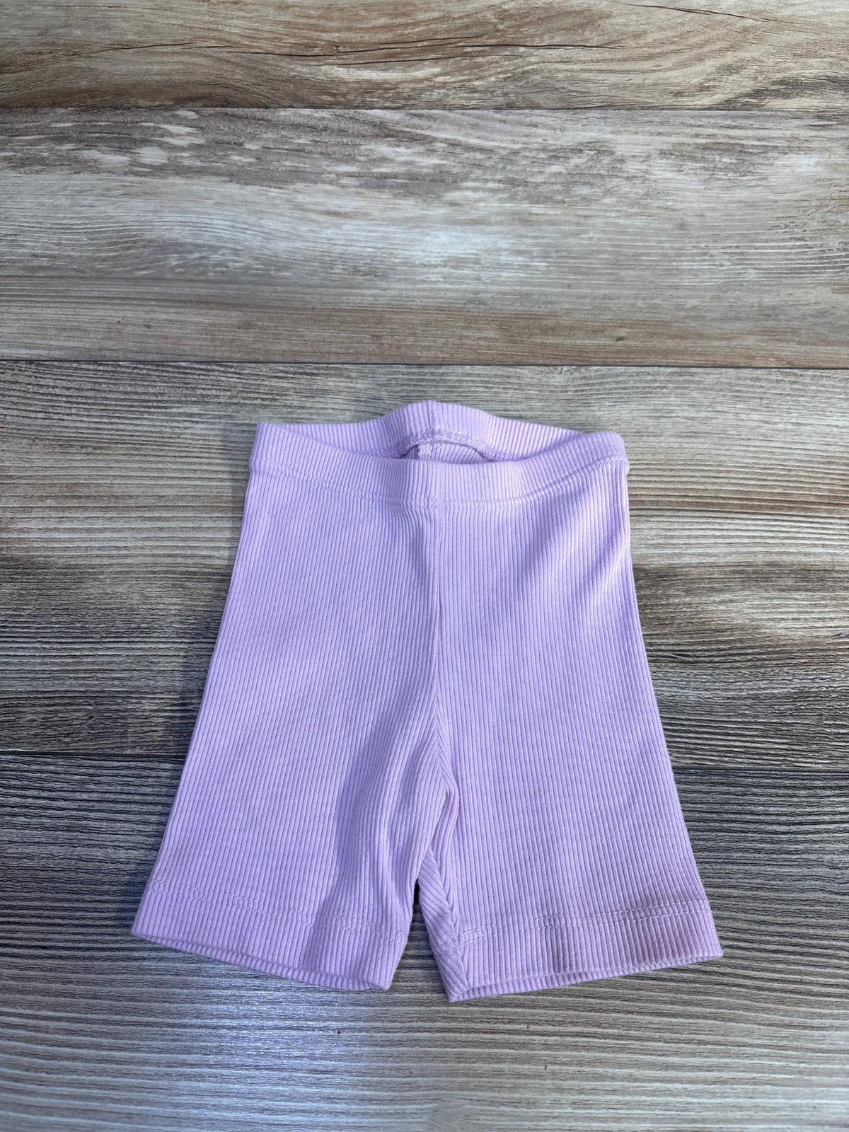 Cat & Jack ribbed bike shorts in pink for baby size 12m on a wooden background