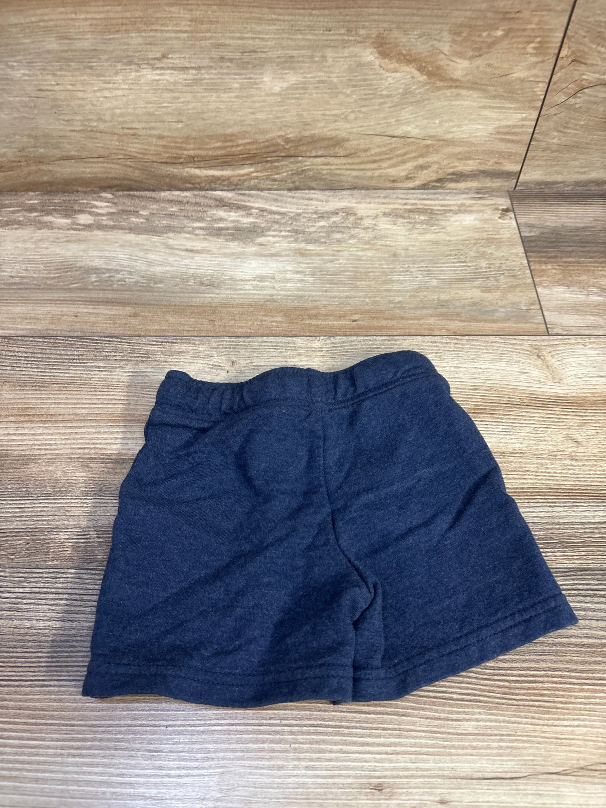Flat lay of navy Cat and Jack knit shorts size 18 months showing elastic waistband and knit texture on wood floor