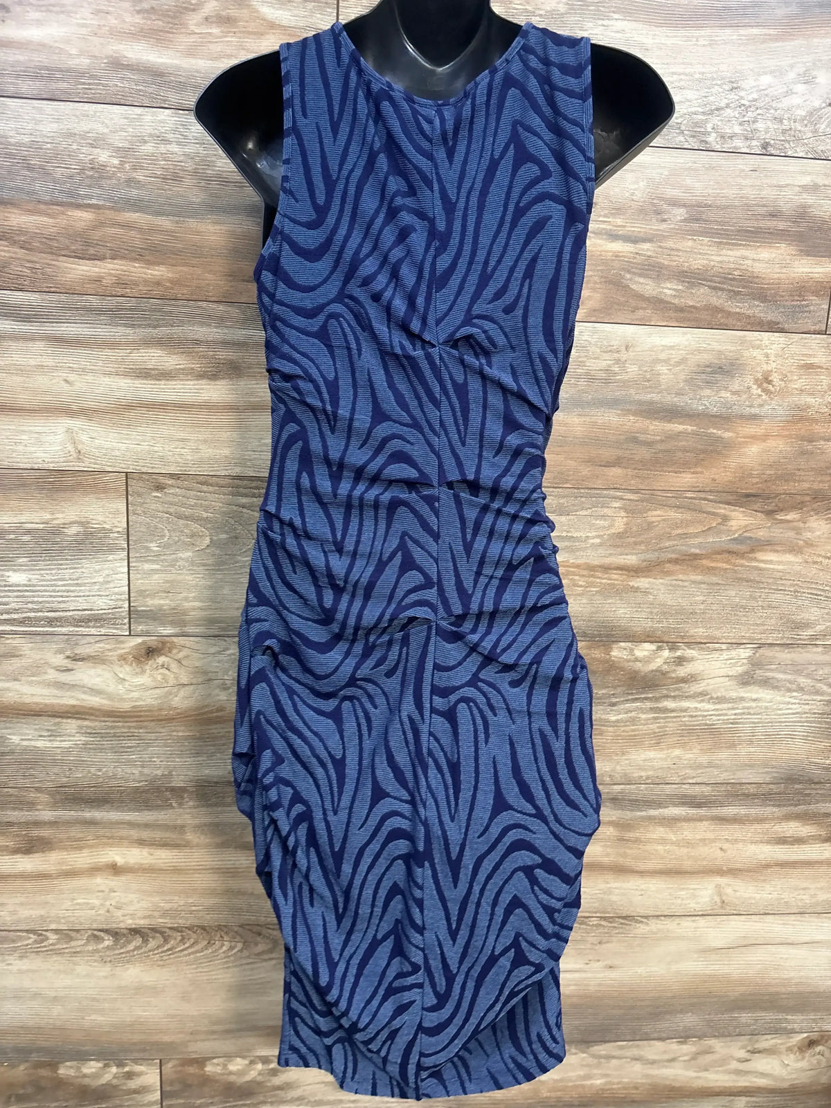 Front view of A Pea In The Pod textured maternity bodycon dress in blue showing zebra-like texture and side ruching on wood