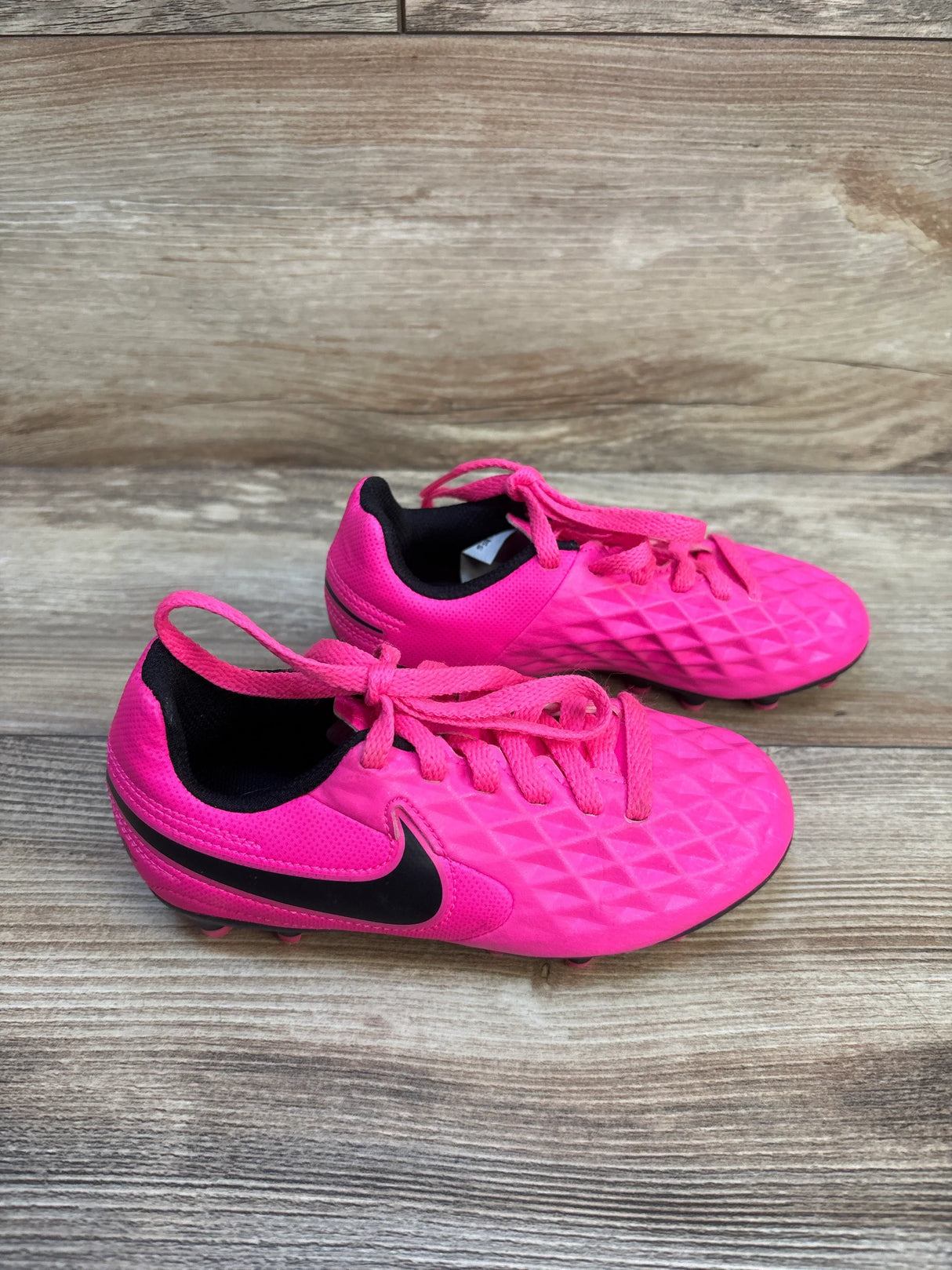 Bright pink kids soccer cleats with black swoosh, perfect for young athletes and sports gear resale.