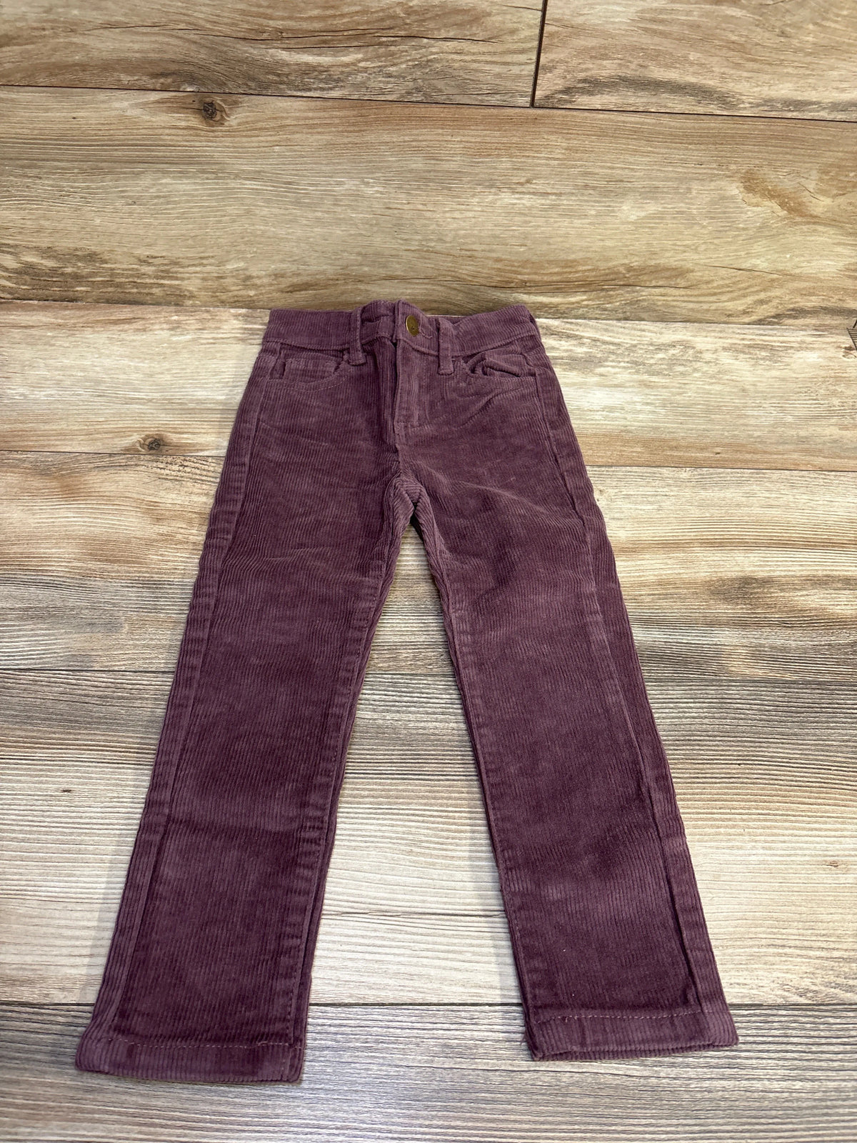 Front view of Jamie Kay purple corduroy pants in size 3T showcasing front pockets and button closure on a wood-grain background