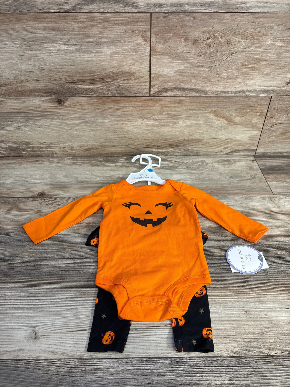 Front view of orange Koala Kids 2pc bodysuit and pants set showcasing a jack-o-lantern bodysuit and pumpkin print pants