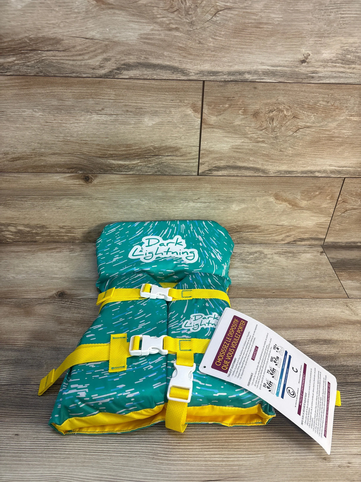 Kids teal and yellow life jacket with safety straps and Dark Lightning logo on wooden floor