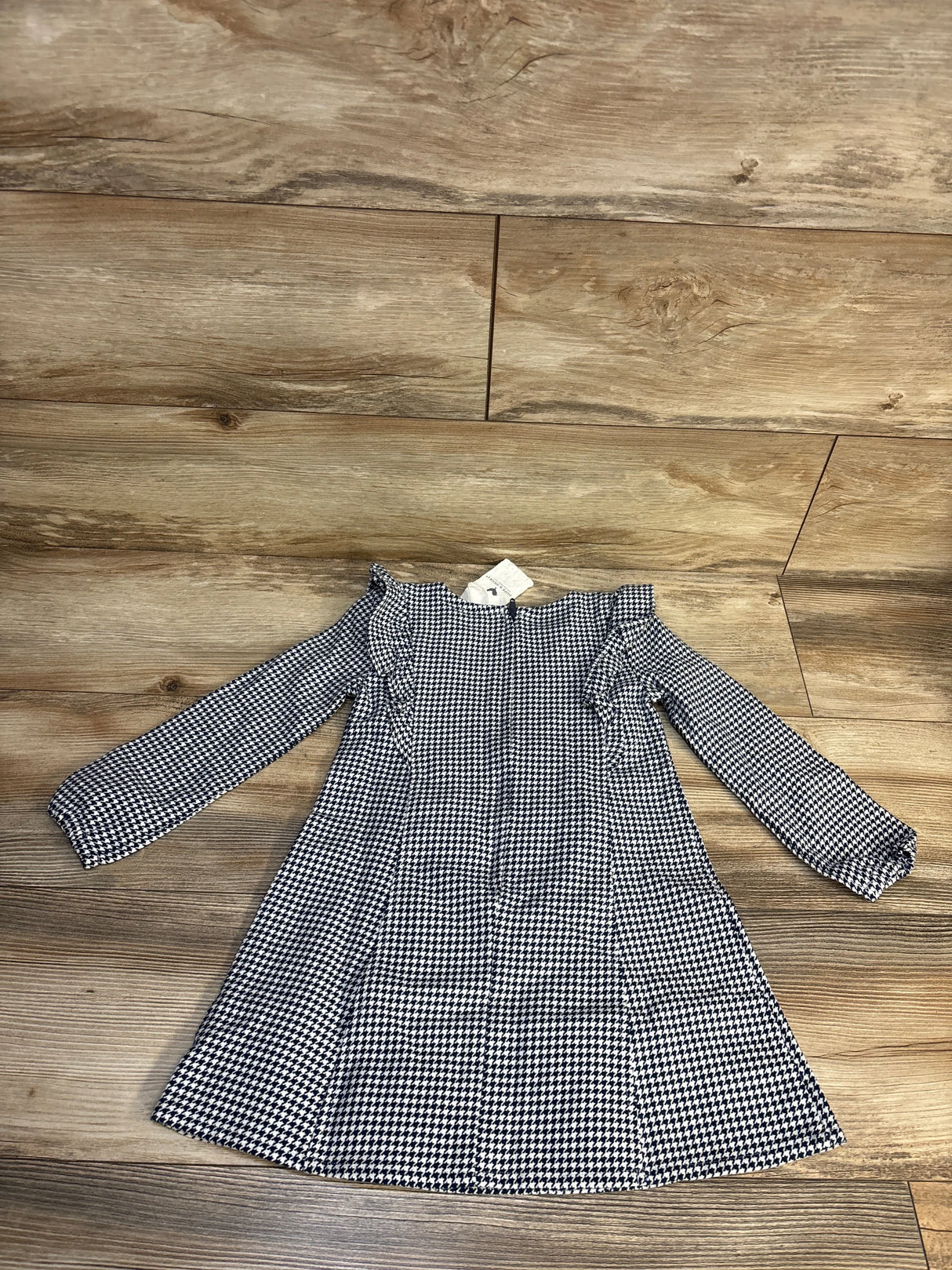 Long sleeve black and white houndstooth girls dress on wood floor