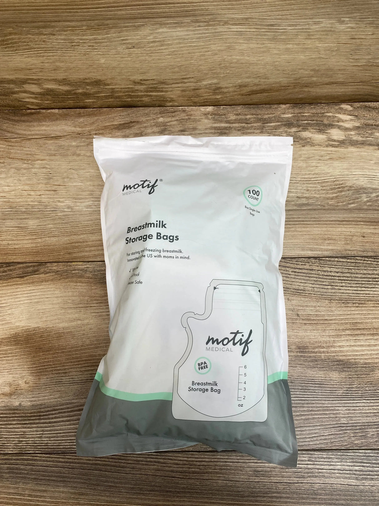 Front view of Motif Medical breastmilk storage bags 100 count pack showing measurement markings and BPA free label on wood background