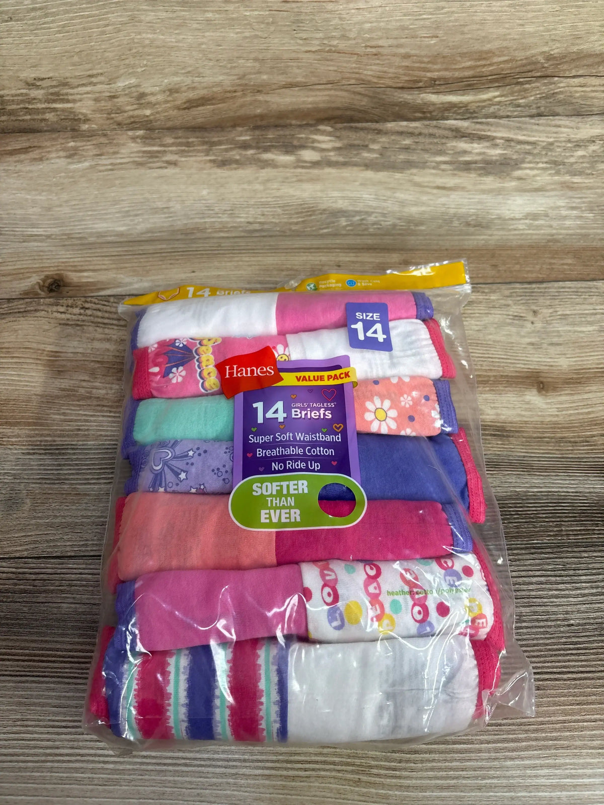 Top-down of Hanes 14-pack girls' tagless briefs showing assorted colorful patterns, size 14 label, on wood surface