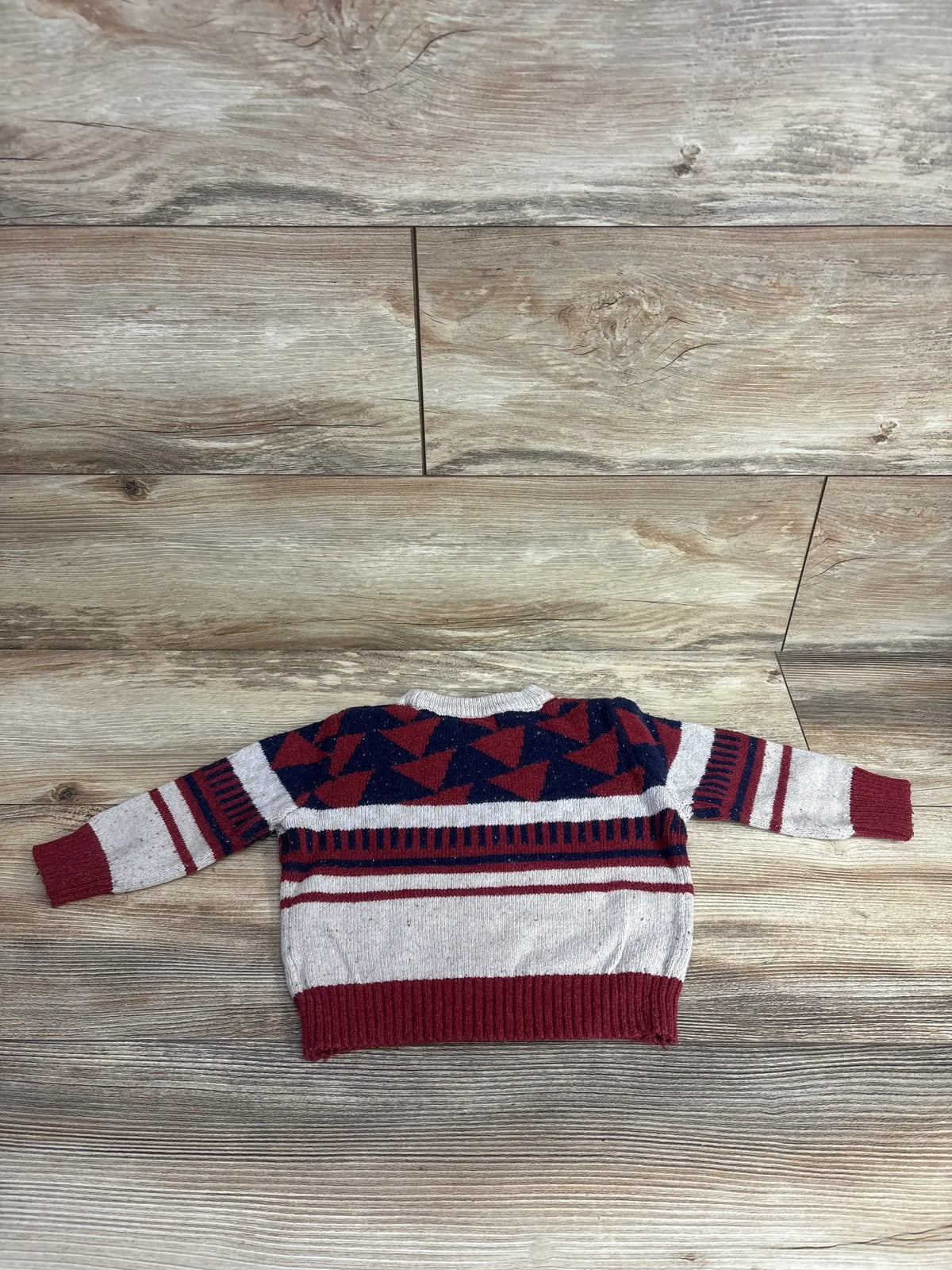Red and navy geometric patterned toddler sweater on wood background