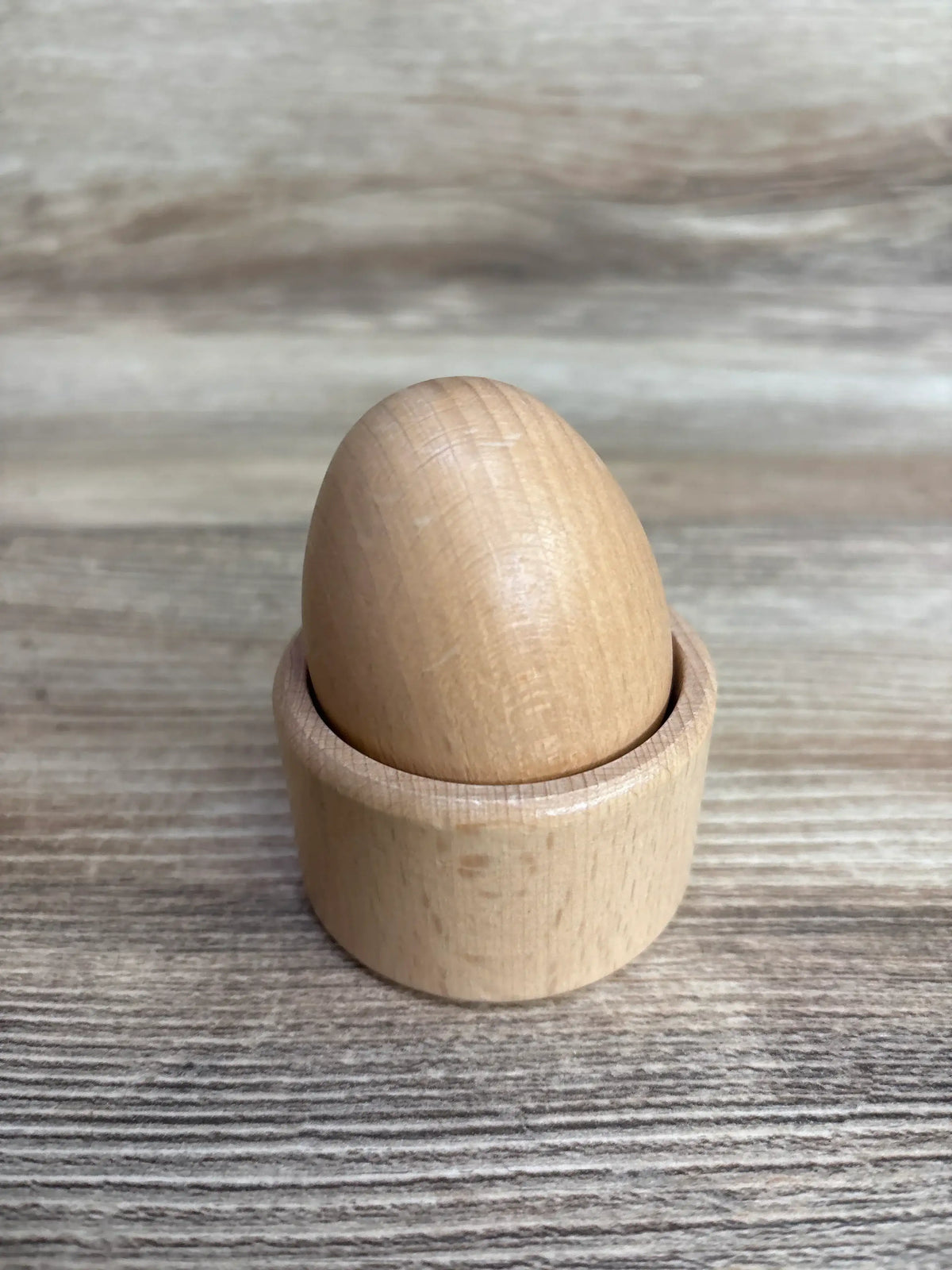Wooden egg toy in wooden cup on tabletop, Montessori play set for kids