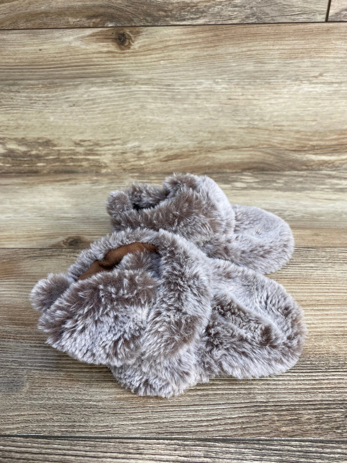 Plush gray baby booties on wood background, cozy infant footwear
