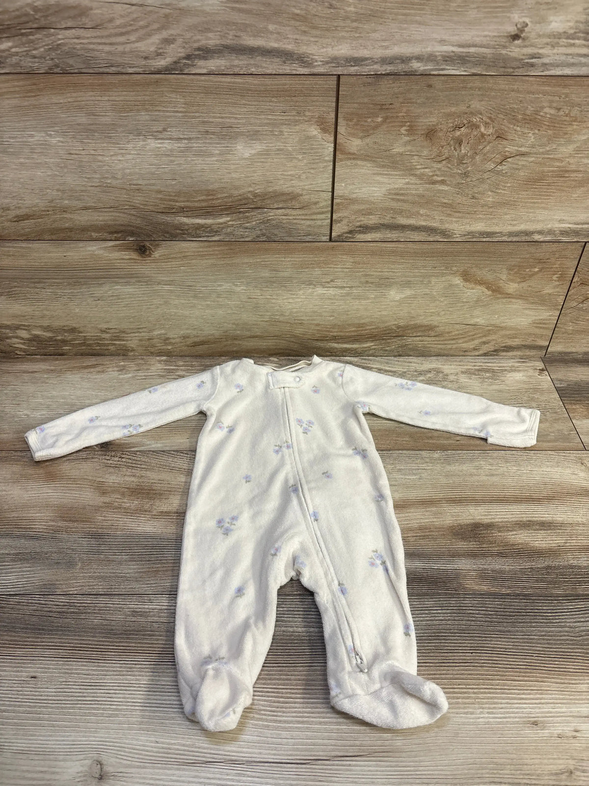 Carter's terry cloth baby sleeper in cream with small blue floral prints on a wood background