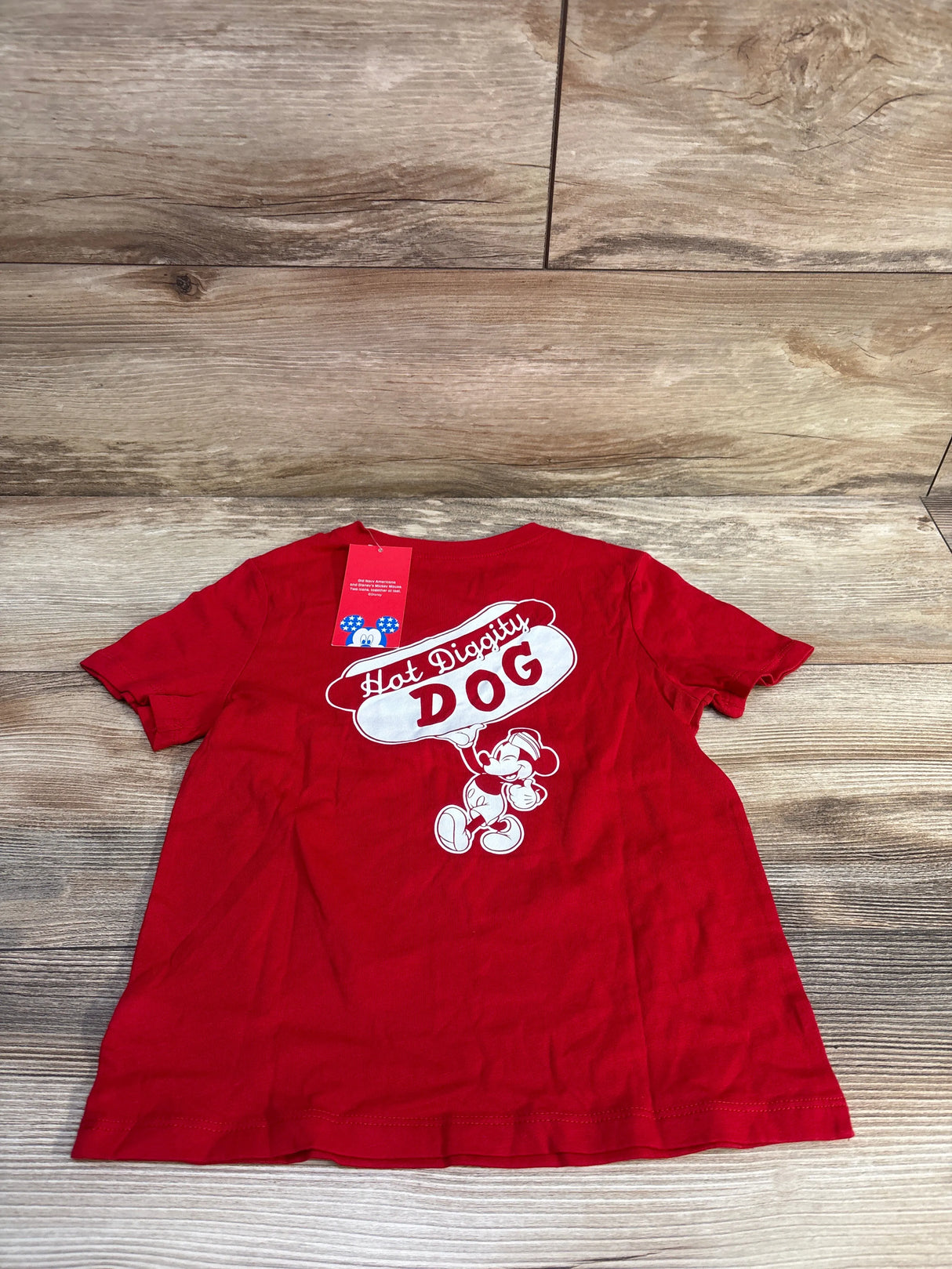 Flat lay of red toddler Mickey Mouse t-shirt showing back Hot Diggity DOG graphic on wood background
