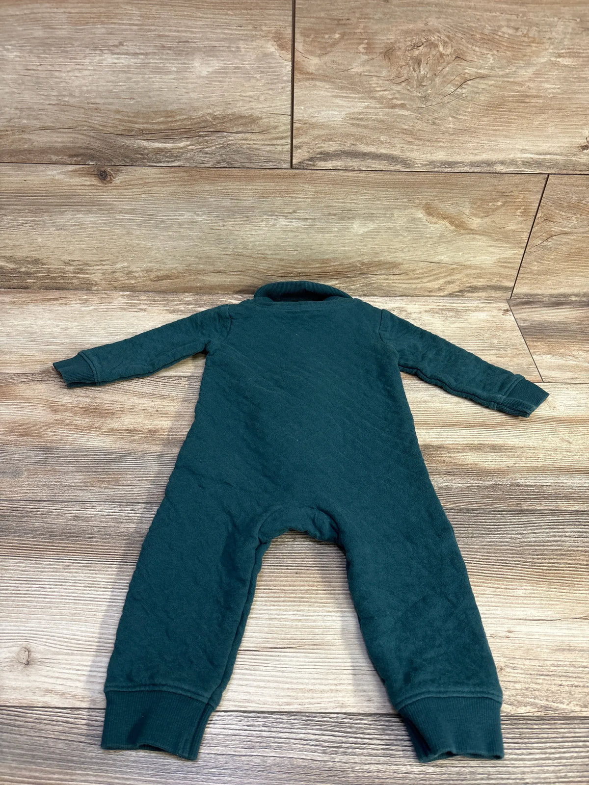 Emerald green Carter's button-front baby coverall laid flat on a wood-grain surface.