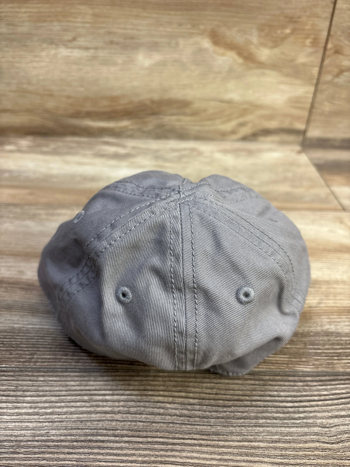 Rear view of Old Navy baby baseball cap (12-24 months) showcasing stitched panels and embroidered eyelets on a woodgrain surface