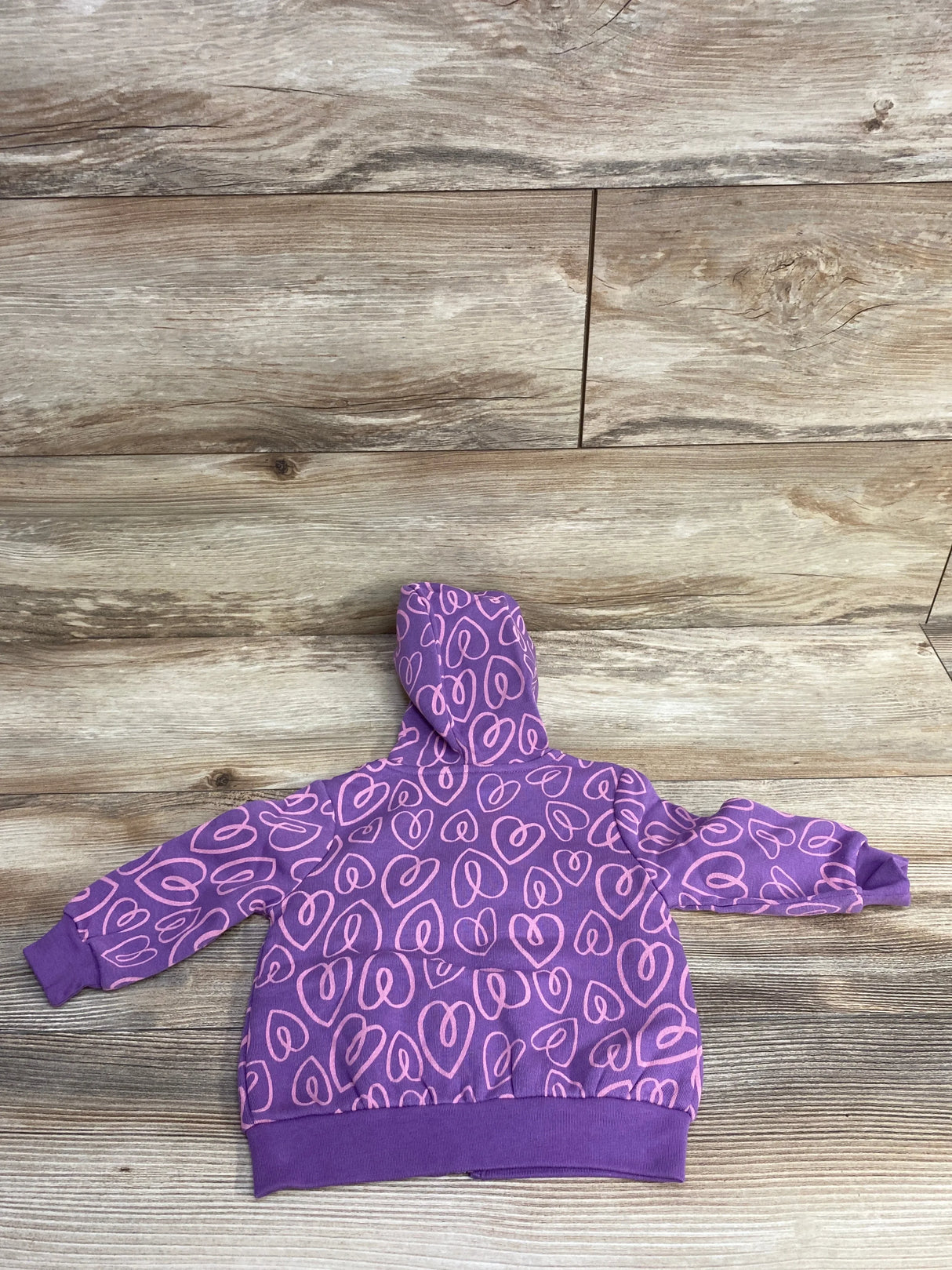 Purple toddler hoodie with pink heart prints on wooden floor, kids clothing