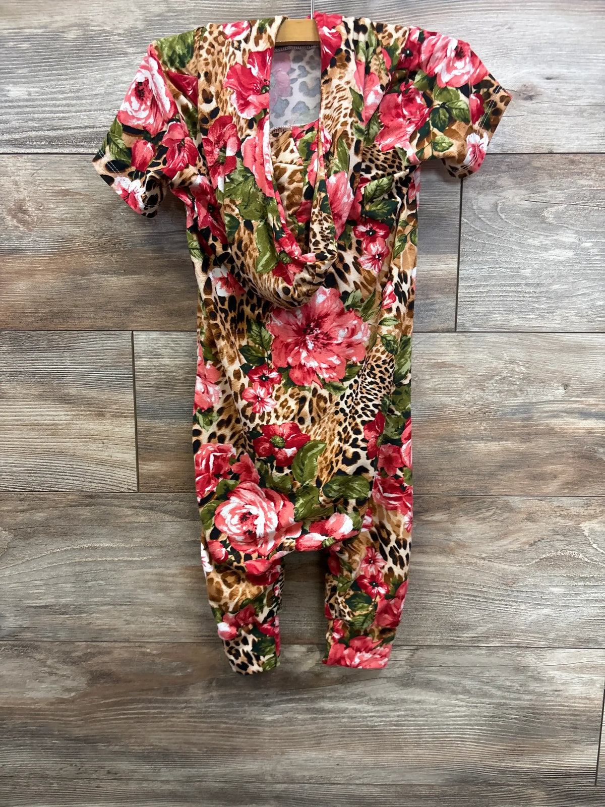 Front view of La Tea Da hooded jumpsuit size 3T showcasing red floral and leopard print, short sleeves, and hood on wood background