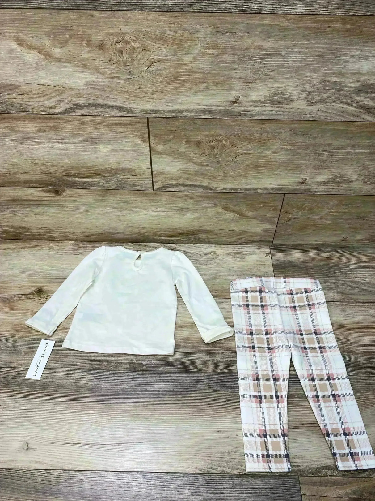 Flat lay of cream long-sleeve fox tee and pink-beige plaid ponte leggings showcasing keyhole back detail on wood floor