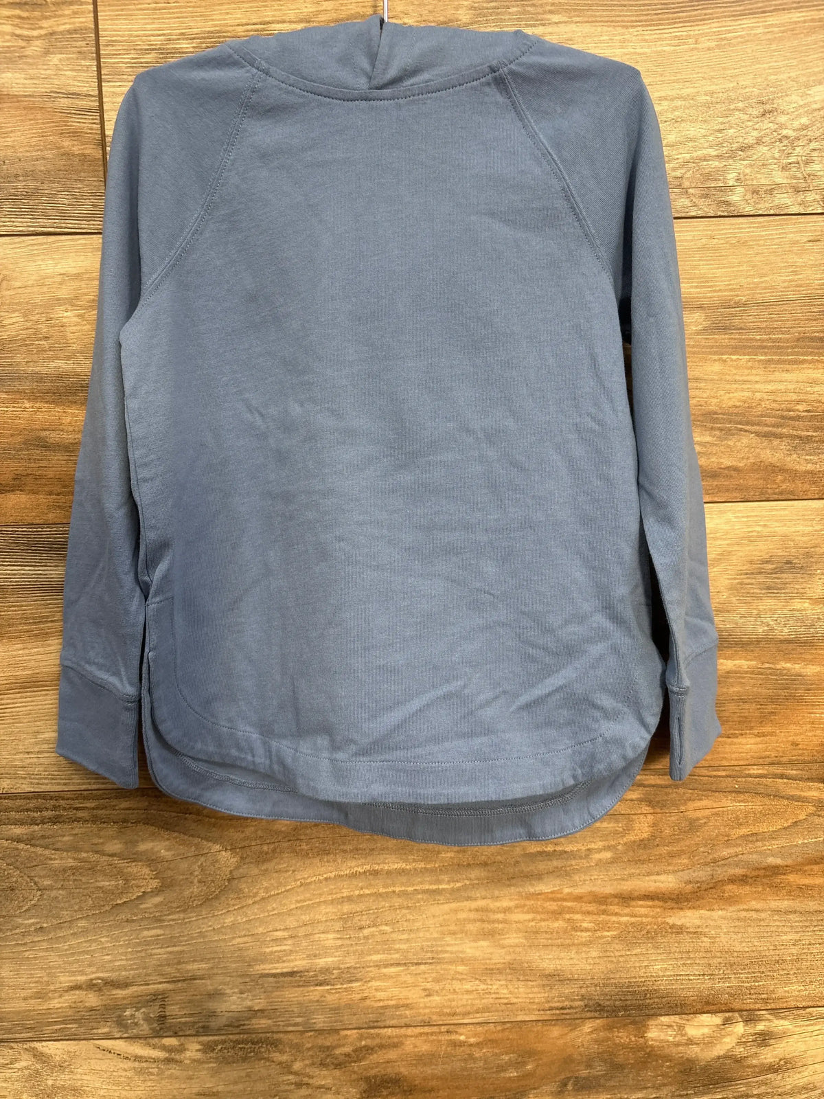Front view of Crewcuts light blue hooded shirt with long sleeves raglan seams and curved hem on wooden background