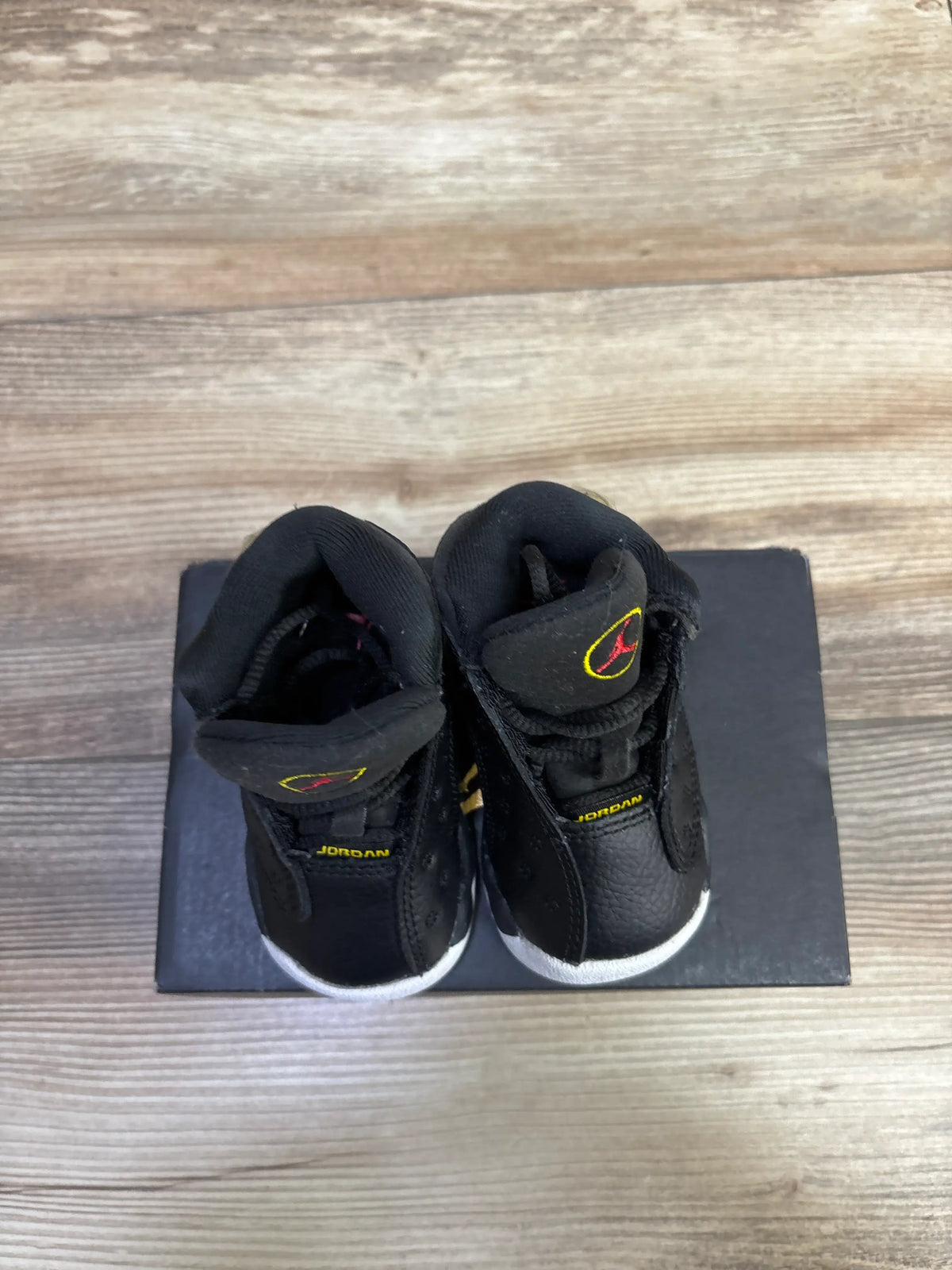 Top view of Air Jordan 13 Retro TD Playoff sneakers showcasing black uppers, white midsoles, and red and yellow branding