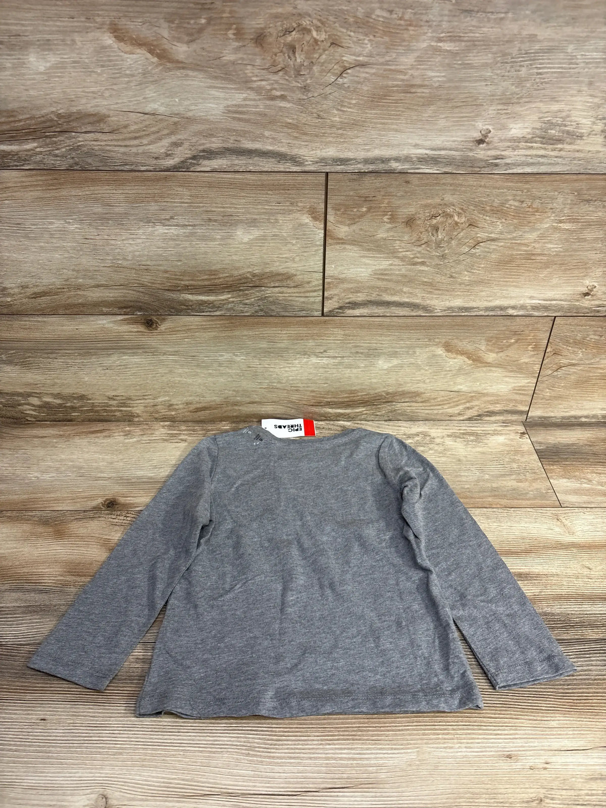 Gray long-sleeve kids shirt on wooden floor, ideal for resale shopping