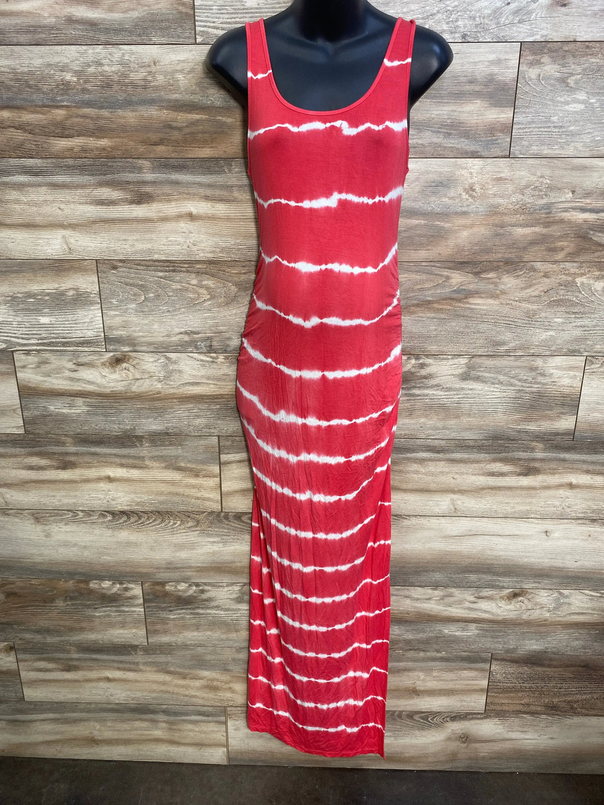 Front view of red tie-dye maternity maxi dress, sleeveless fitted silhouette on black mannequin with wood background