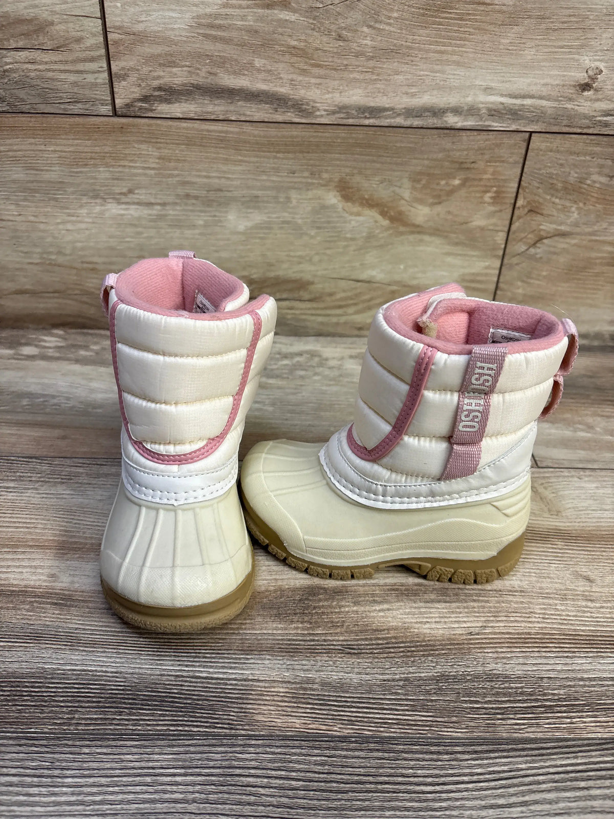 Front and side view of Oshkosh Splash kids winter boots in ivory with pink trim, rubber sole on wood floor