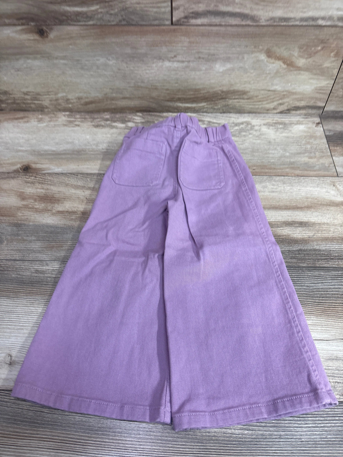 Rear view of Nordstrom wide-leg pants in lavender, size 4T, showcasing elastic waist and two back pockets on a wood floor