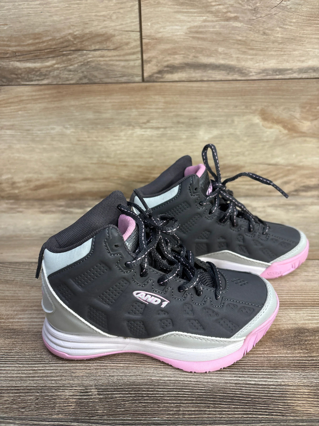 Pair of black and pink AND1 basketball sneakers on wood floor background