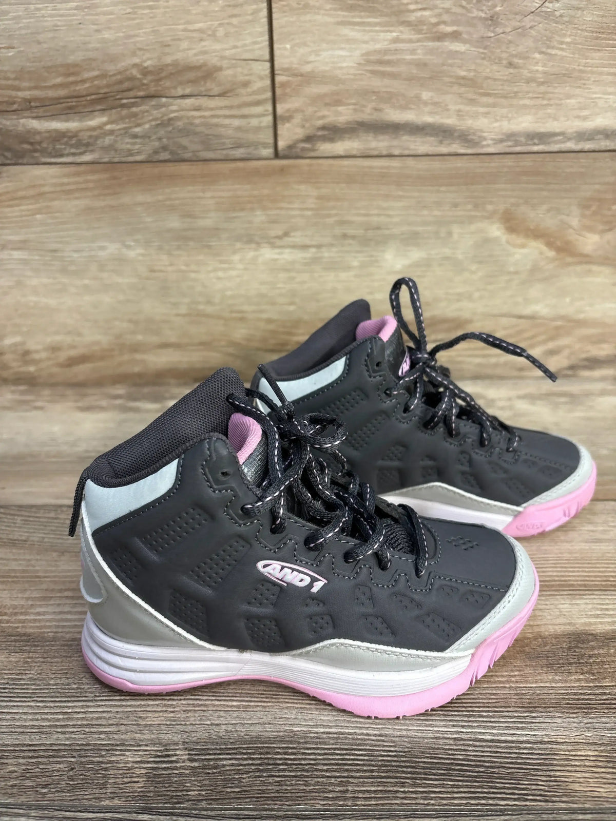Three-quarter view of AND1 Showout basketball shoes size 12C showcasing high-top ankle support and pink outsole with wooden floor background