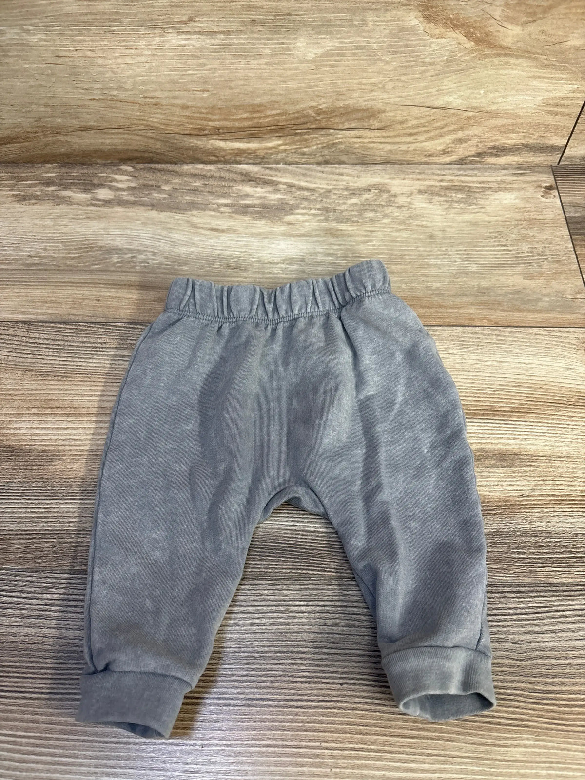 Front flat lay of newborn grey Cat and Jack pull-on joggers showing elastic waistband and cuffed ankles on wood background