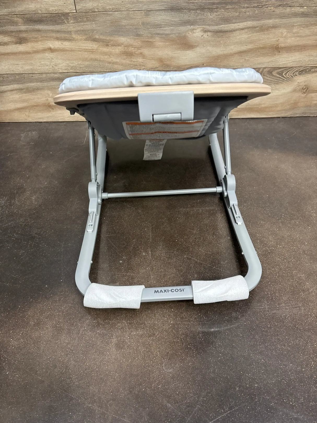 Rear view of Maxi-Cosi Kori 2-in-1 baby rocker showing grey metal frame and seat with Maxi-Cosi logo on foot bar