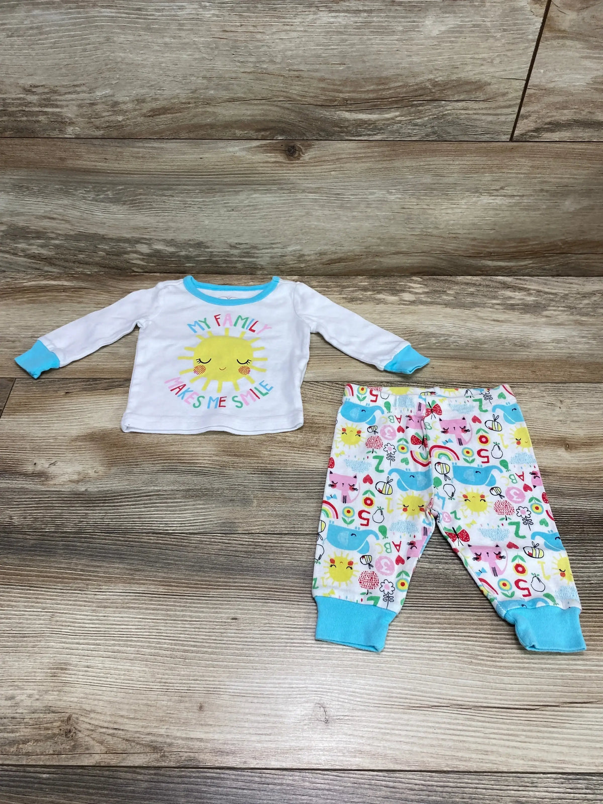 Front view of Children’s Place 2-piece white infant pajama set showing My Family Makes Me Smile print on top against plain background