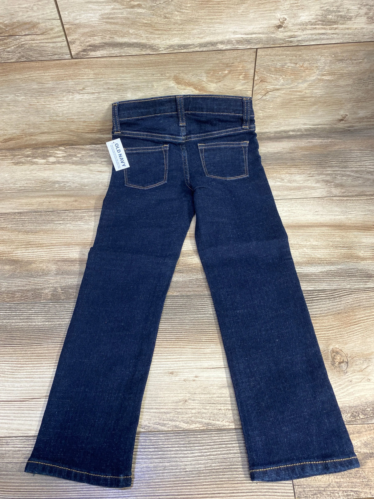 Dark wash kids denim jeans with back pockets and Old Navy tag on wood floor