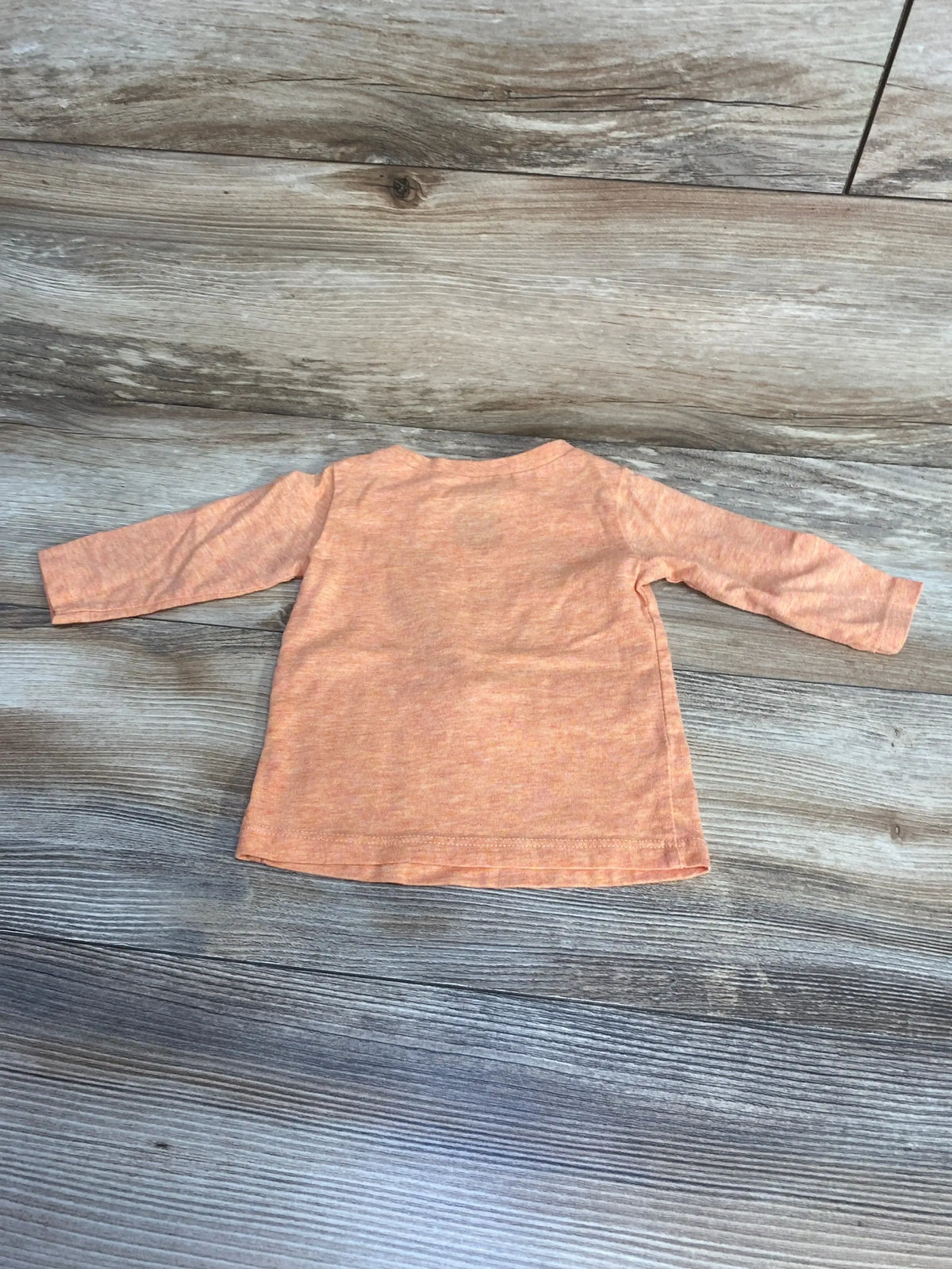Front view of First Impressions Pumpkin Shirt in orange, showcasing long sleeves on a wood-look floor