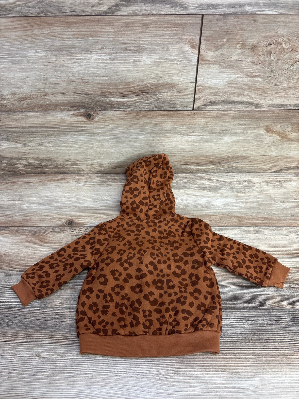 Back flat-lay of Okie Dokie leopard print full-zip baby hoodie size 3-6 months showing hood, long sleeves, and ribbed hem on wood floor