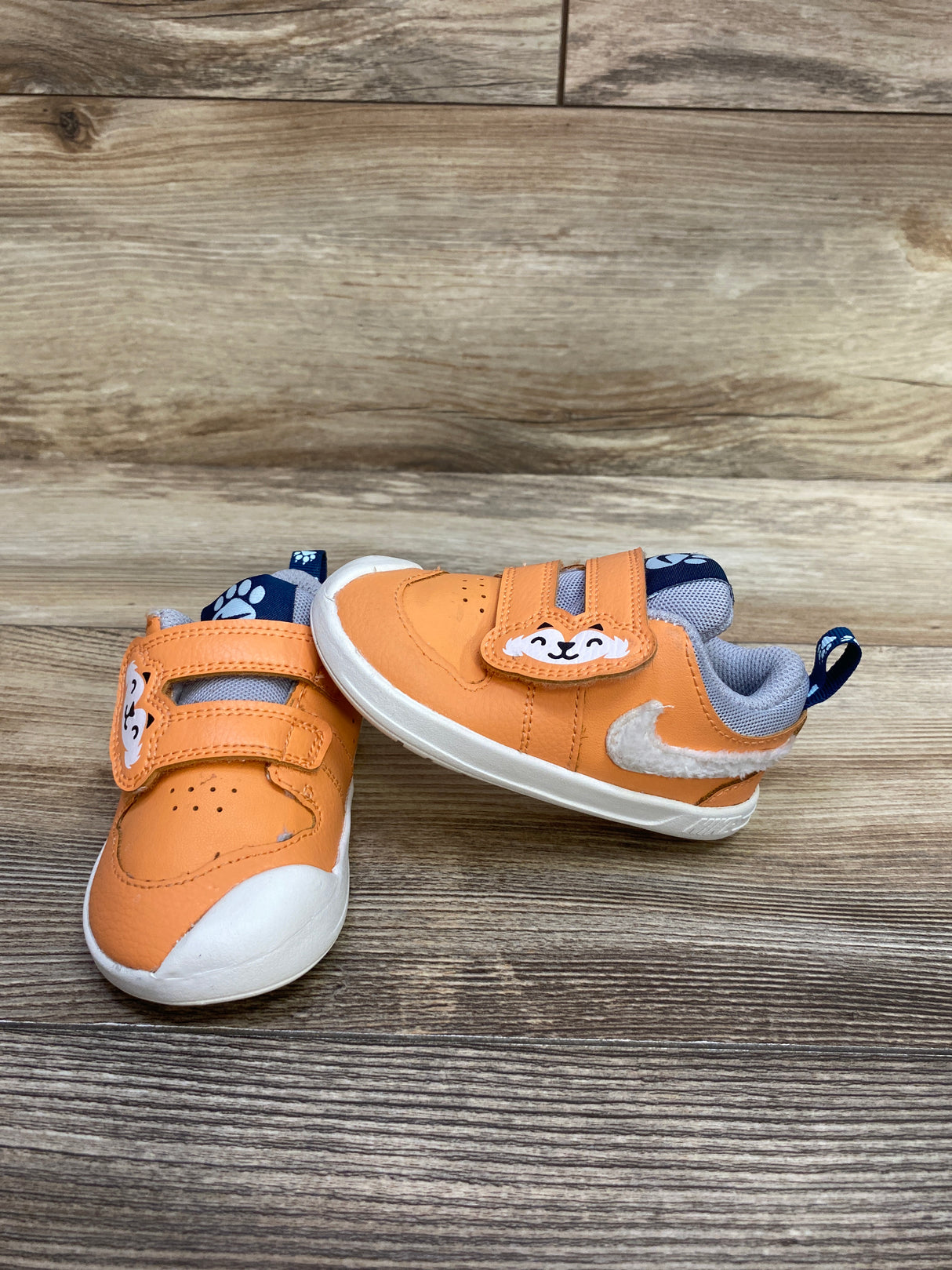 Orange and white toddler sneakers with cute animal face and paw print on blue tongue